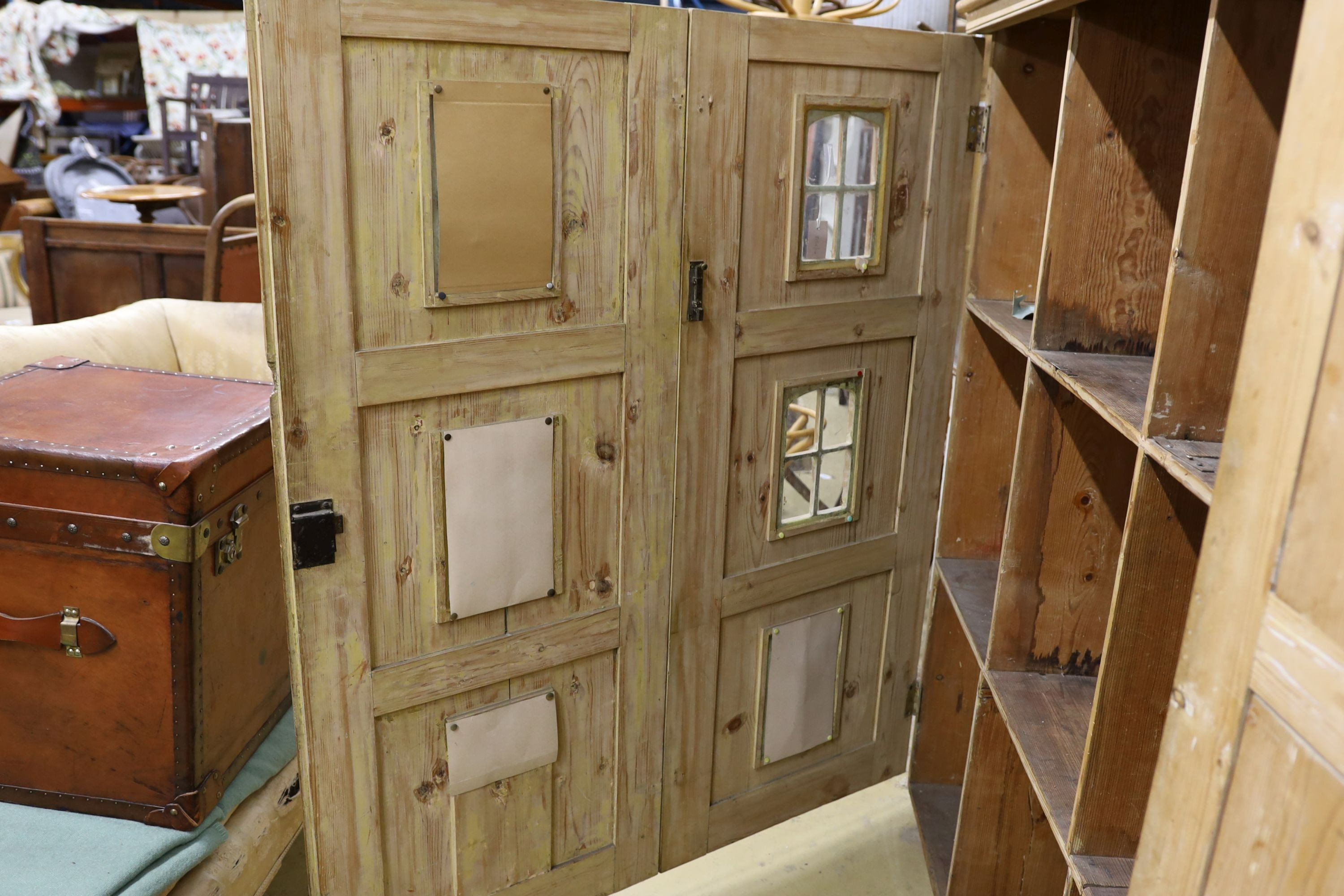 A 19th century stripped pine hall cupboard modelled as a dolls house the two door nine window facade enclosing a compartmented interior, width 182cm, depth 46cm, height 192cm